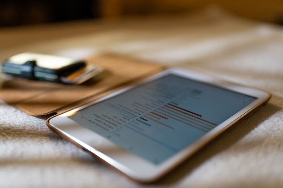Tablet prikazuje financijske grafove na bijeloj podlozi